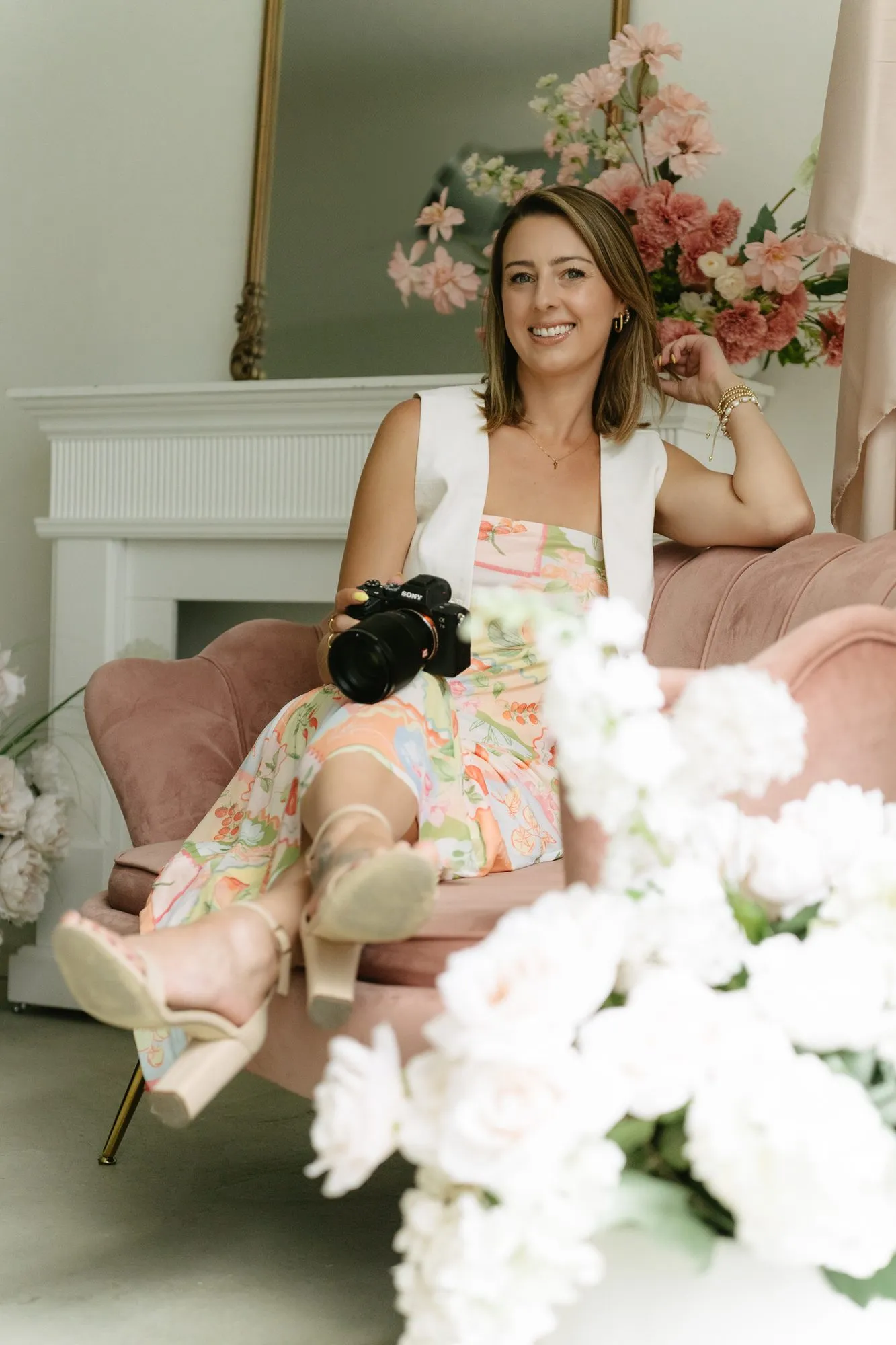 Shelby seated with her camera among pink flowers